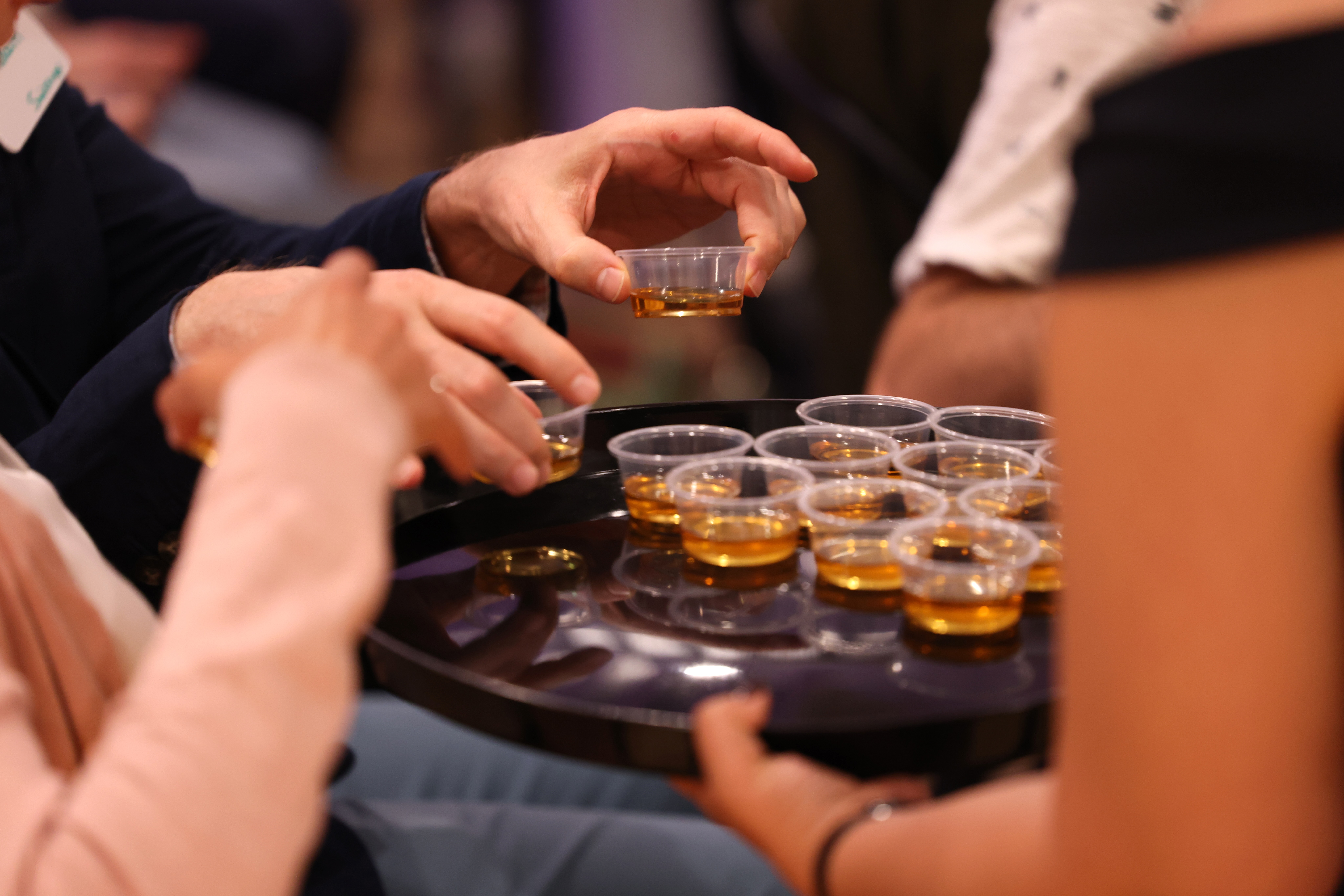 Hands reaching for maple syrup tasting samples